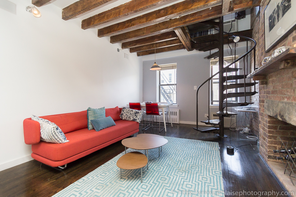 Professional photography of living room taken in the East Village of New York City, with exposed beams and brick wall